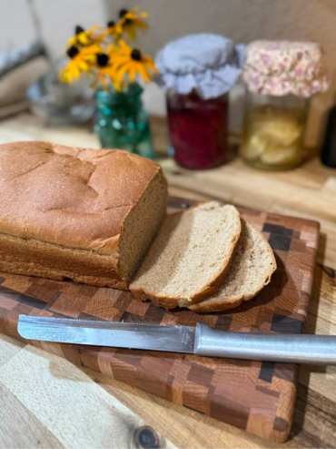 a loaf of bread with some pieces sliced on a wooden cutting board