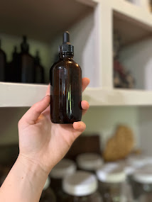 somebody holding a dropper bottle out from a shelf with other dropper bottles